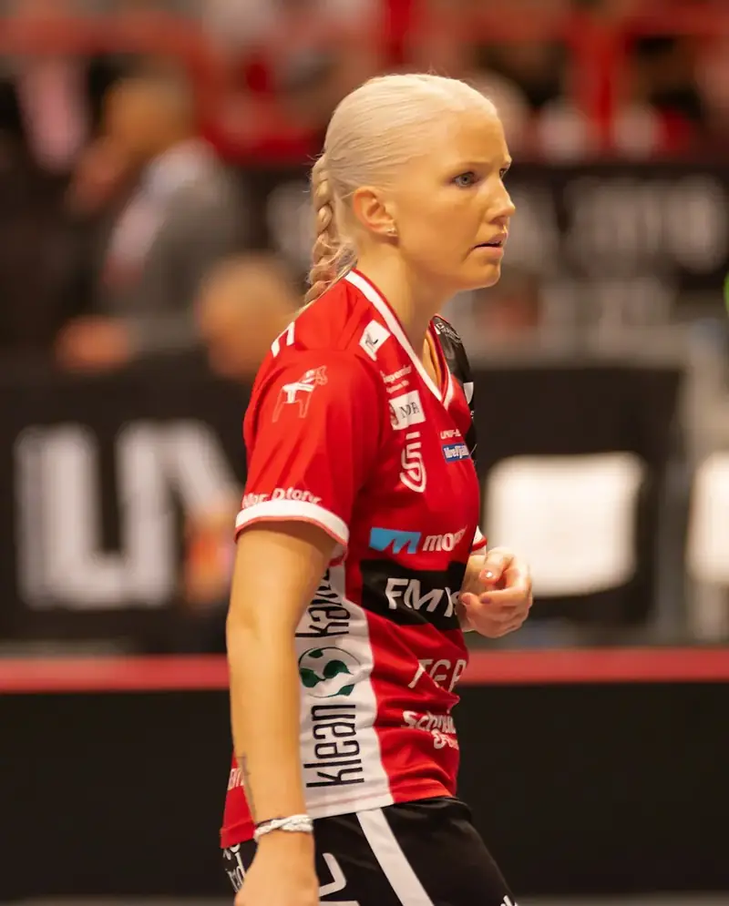 Innebandyspelare i röd matchtröja koncentrerar sig framför sargen under matchen